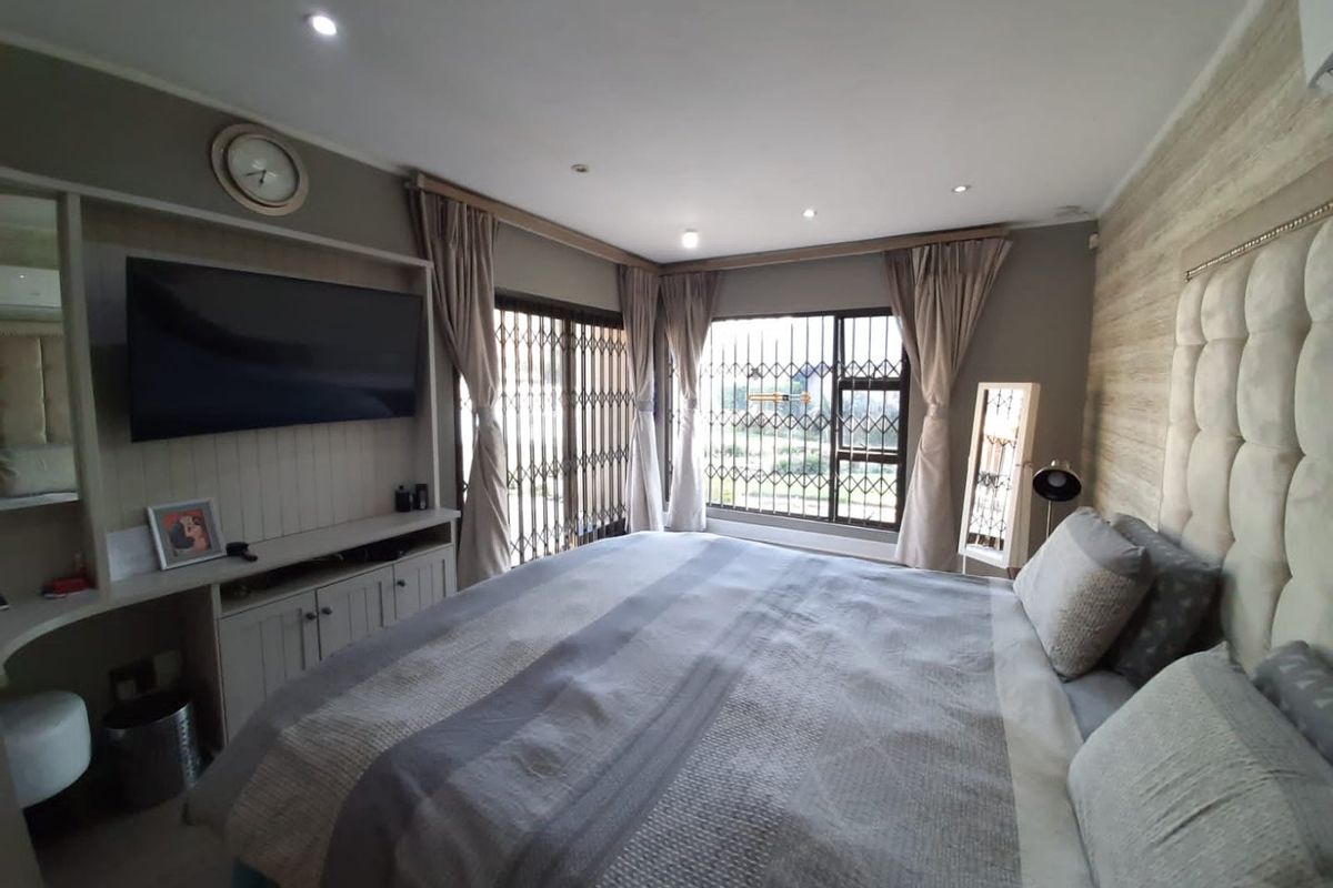 A well-maintained bedroom featuring built-in cabinetry, recessed ceiling lighting, and security gates on the windows.