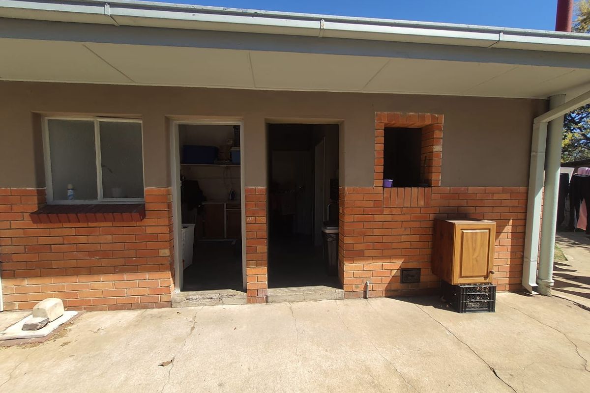 Rear exterior view showing a concrete patio area with access to utility spaces, featuring brick facade detailing and a small built-in brick niche.