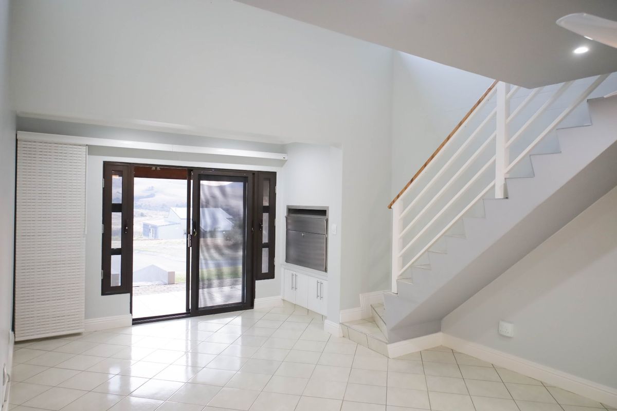 Bright open-plan living area featuring a staircase, built-in fireplace, and sliding glass doors leading to the exterior.