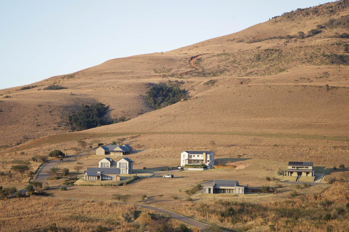 An aerial view of a residential estate featuring multiple modern homes set against a scenic, hilly landscape.