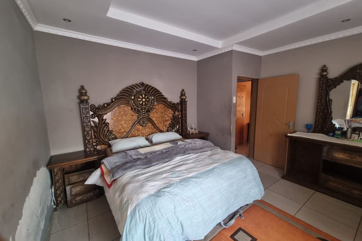 A bedroom featuring tiled flooring, recessed ceiling lighting, and decorative crown molding, with visible wear on the lower wall sections.