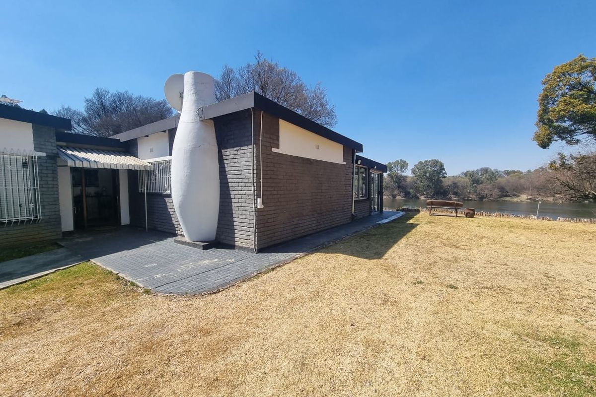 Rear view of the farm property featuring a paved patio area, brick exterior walls, and direct access to the riverfront landscape.