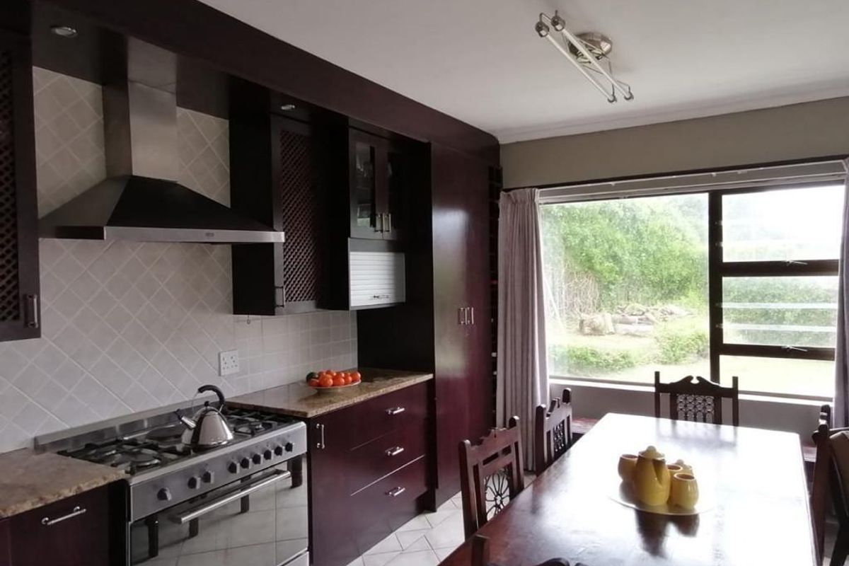 A well-appointed kitchen featuring dark wood cabinetry, granite countertops, a stainless steel gas stove with extractor fan, and tiled flooring.