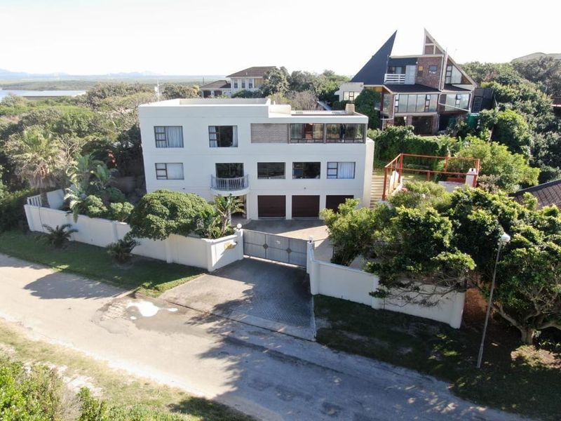 Aerial view of a multi-story residential property featuring a triple garage, balcony, and enclosed garden area with perimeter walling.