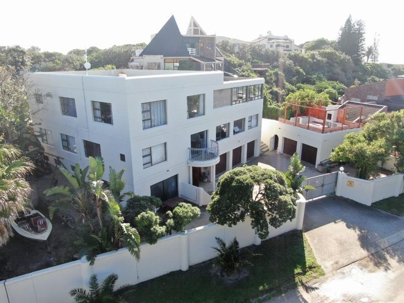 Aerial view of a multi-story residential property featuring a white facade, multiple garage bays, a balcony, and a rooftop terrace area.