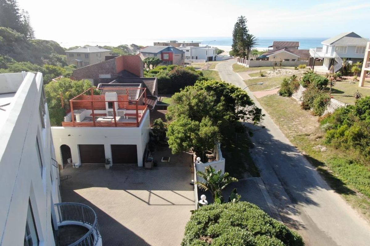 Elevated aerial view of the property showing the driveway, double garage with rooftop terrace, and surrounding coastal neighborhood landscape.