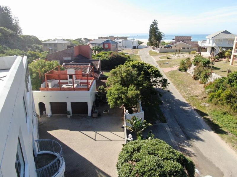 Elevated aerial view of the property showing the driveway, double garage with rooftop terrace, and surrounding coastal neighborhood landscape.