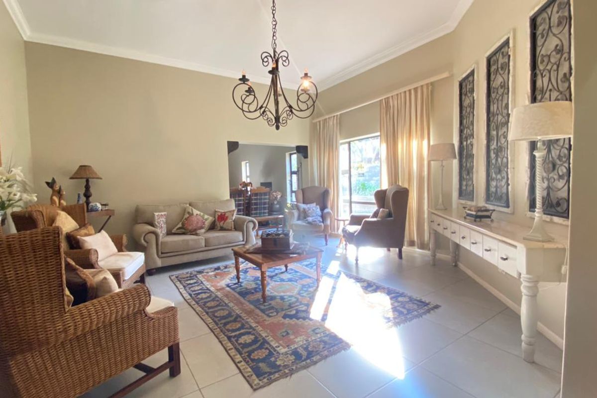 Spacious living room featuring neutral walls, tiled flooring, a decorative chandelier, and large windows allowing for ample natural light.
