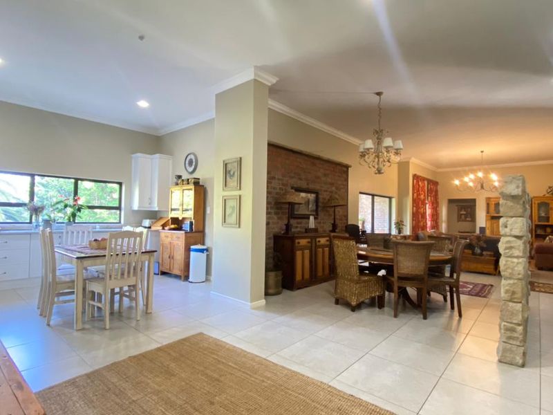 Spacious open-plan living and dining area featuring tiled floors, an exposed brick feature wall, and a functional kitchen with ample cabinetry.