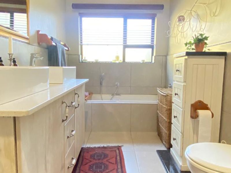 A well-maintained bathroom featuring a double vanity, built-in bathtub, and neutral tiled finishes, offering a functional and clean space.