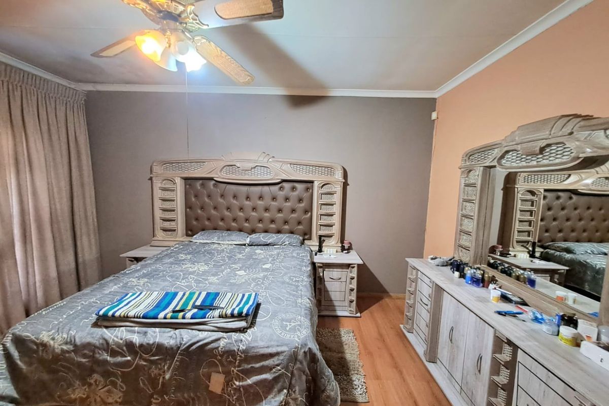 A bedroom featuring laminate flooring, a ceiling fan with integrated lighting, and neutral wall tones.