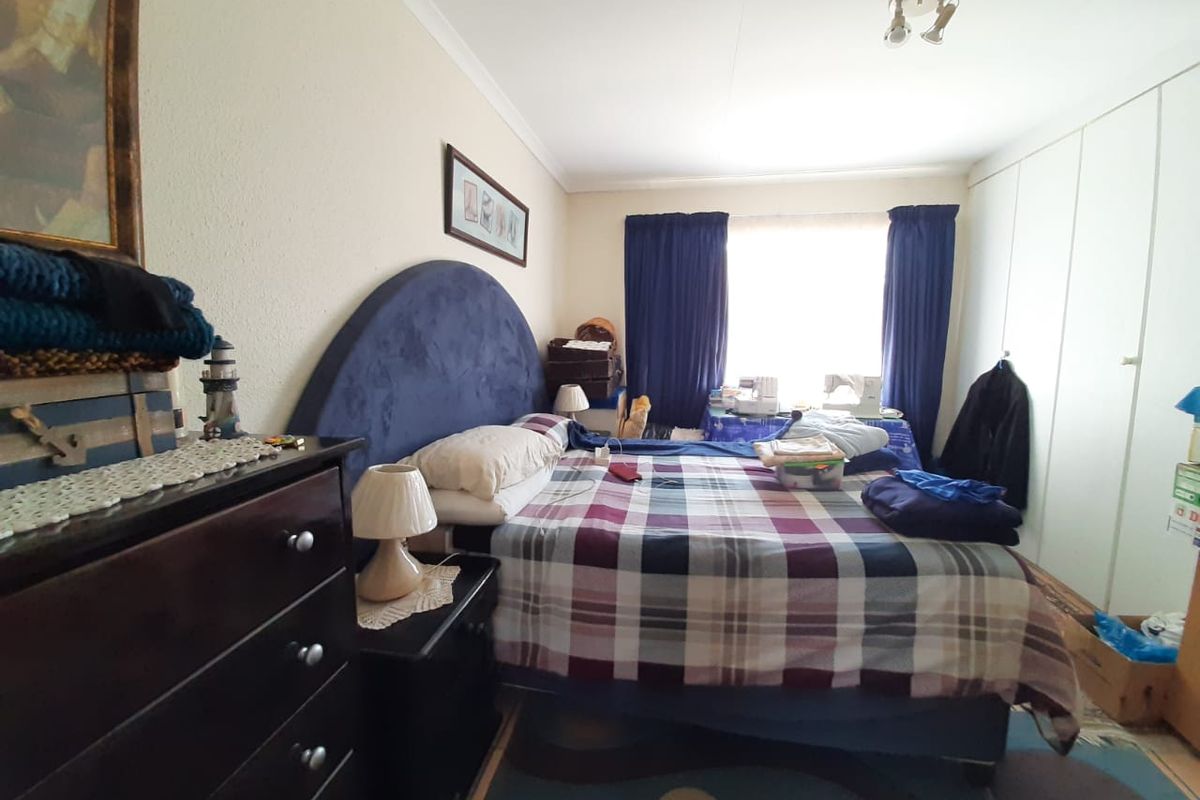 A bedroom featuring built-in cupboards and a window with curtains, providing natural light and storage space.