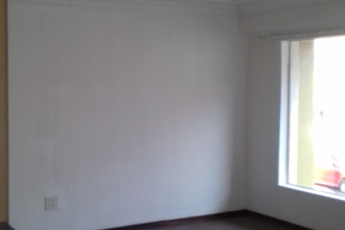 An empty room featuring neutral walls, carpeted flooring, and a window providing natural light.