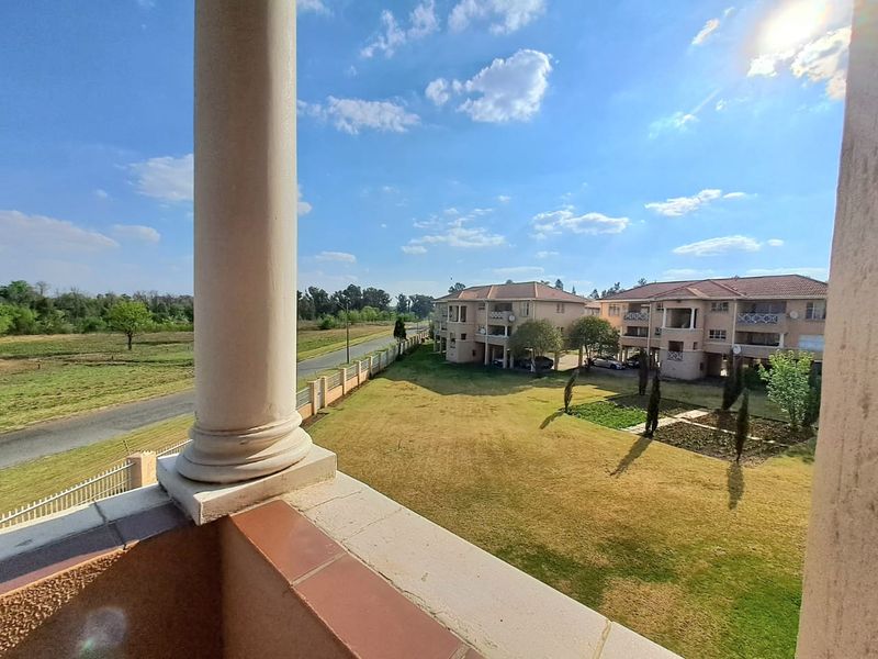 A view from a balcony overlooking a landscaped garden area and neighboring residential buildings.