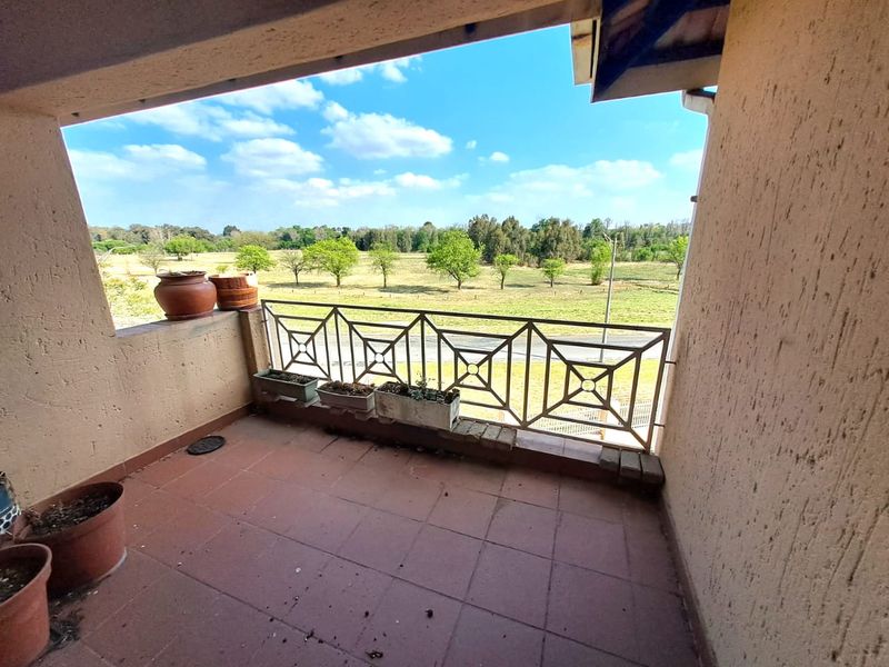 A covered balcony featuring tiled flooring and a metal balustrade, offering an open view of the surrounding landscape.