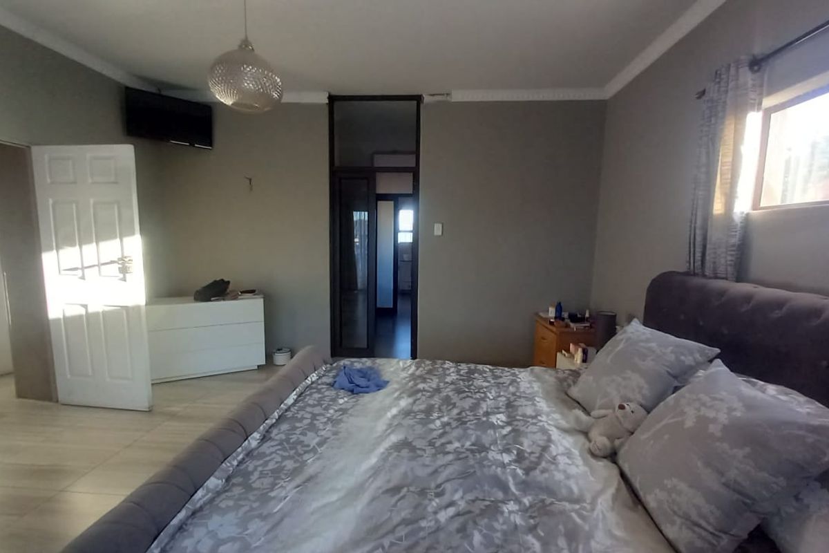 A spacious bedroom featuring neutral wall tones, tiled flooring, and decorative coving, offering a comfortable and functional living space.