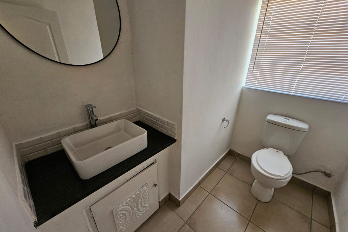 A functional bathroom featuring a modern vessel sink on a dark stone vanity, a standard toilet, and tiled flooring.