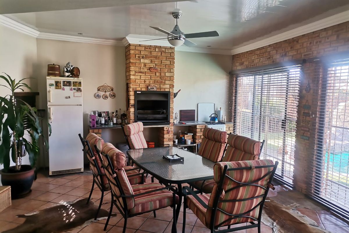 An indoor entertainment area featuring a built-in brick fireplace, tiled flooring, and large sliding glass doors providing access to the outdoor space.