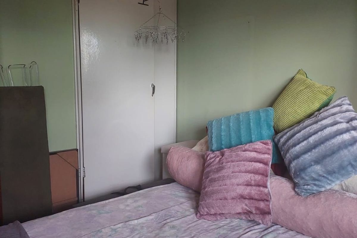 A bedroom featuring a built-in cupboard with overhead storage and light green wall finishes.