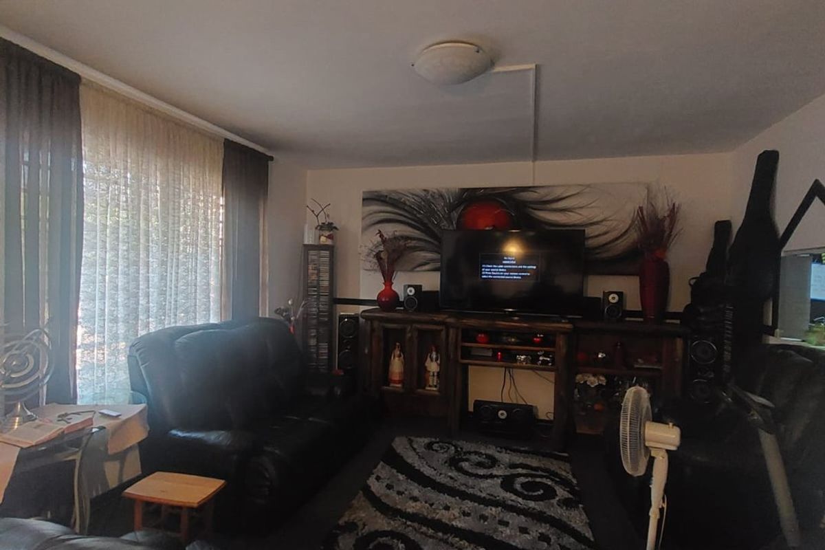 A comfortable living room featuring large windows with curtains, providing natural light and a functional space for relaxation.
