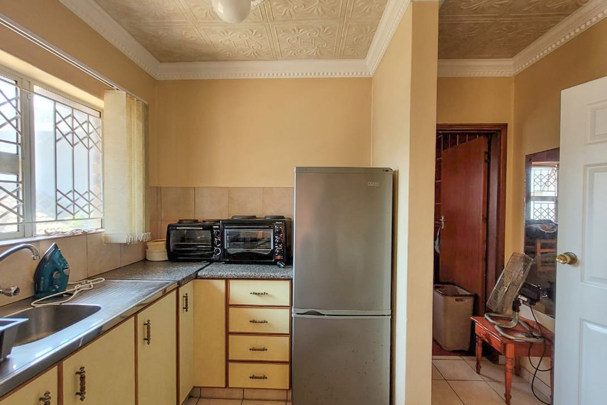 A functional kitchen featuring built-in cabinetry, granite-look countertops, a stainless steel sink, and a tiled backsplash.