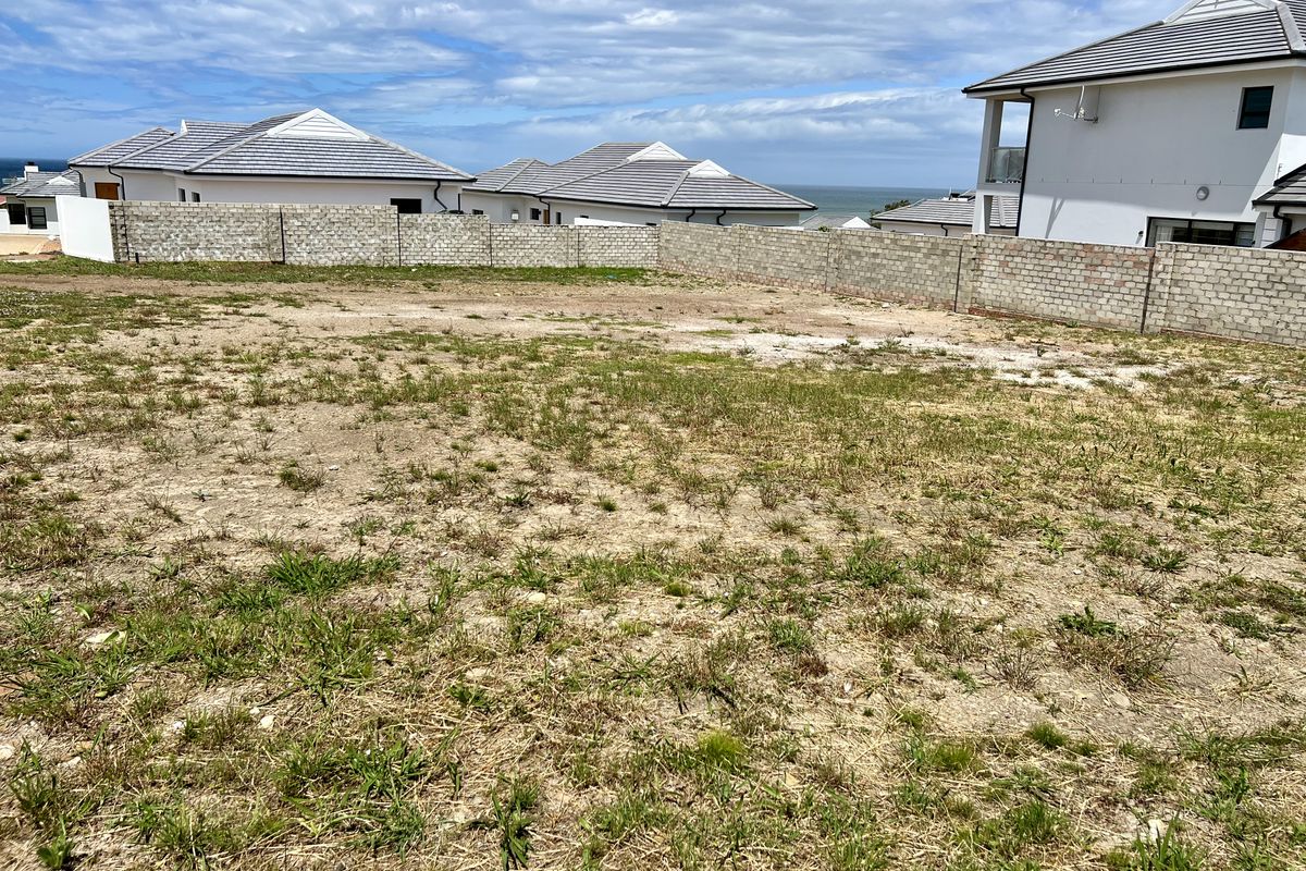 A vacant residential plot featuring a perimeter boundary wall, situated in a developed estate with surrounding residential properties.