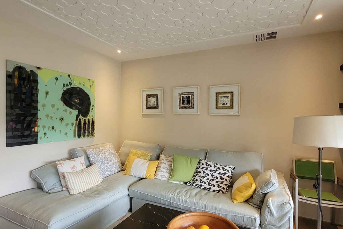 A comfortable living room featuring a decorative patterned ceiling, recessed downlighting, and built-in wall shelving.