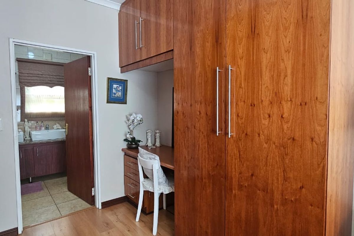 Bedroom featuring built-in wooden cabinetry with integrated desk space and direct access to an en-suite bathroom.