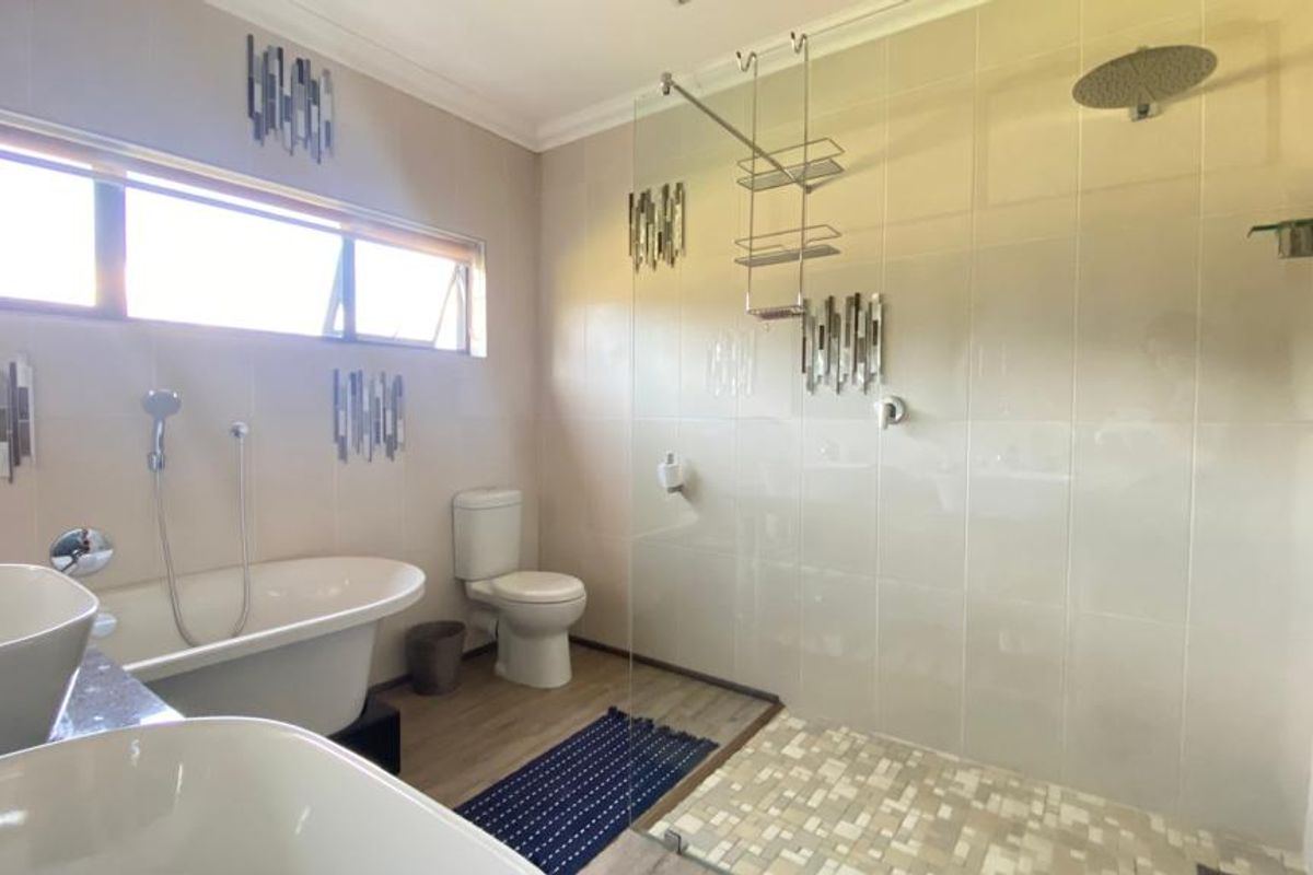 Modern bathroom featuring a freestanding bathtub, spacious walk-in shower with rain shower head, and dual vanity basins with contemporary tiled finishes.