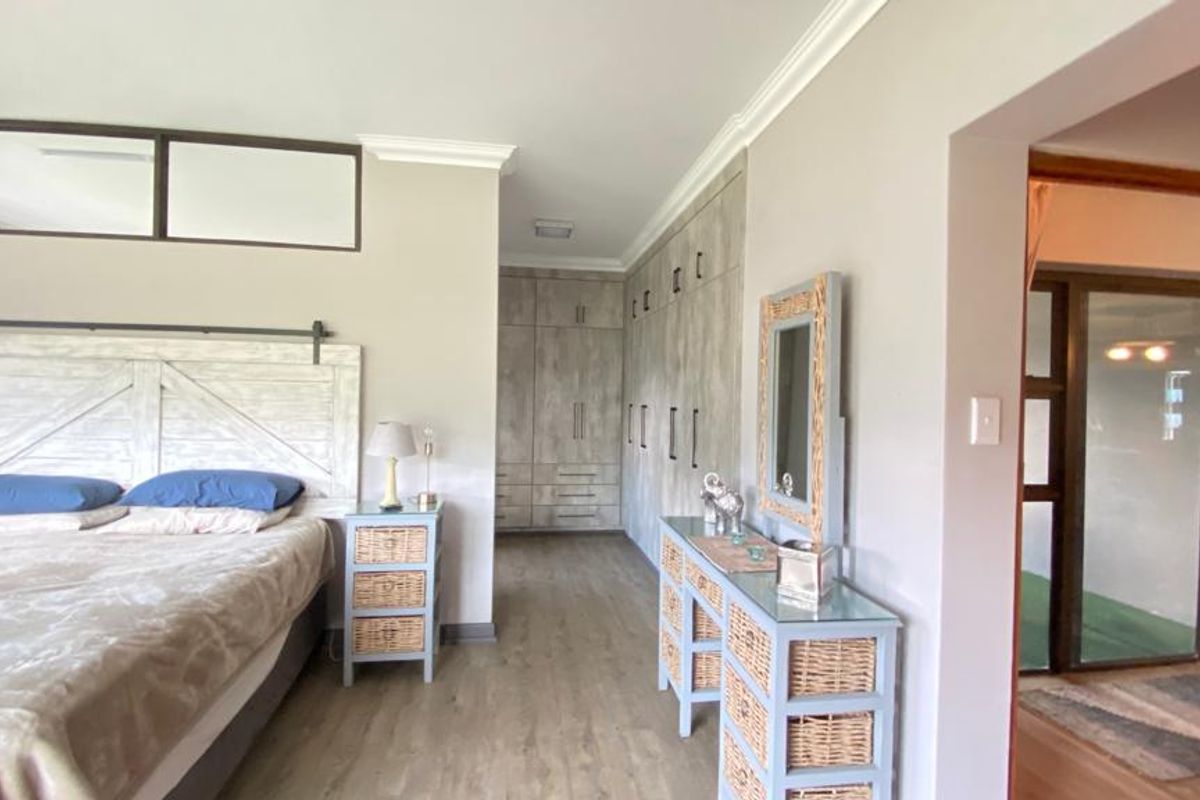 Spacious bedroom featuring extensive built-in cabinetry, modern laminate flooring, and neutral wall finishes with a clean, well-maintained aesthetic.