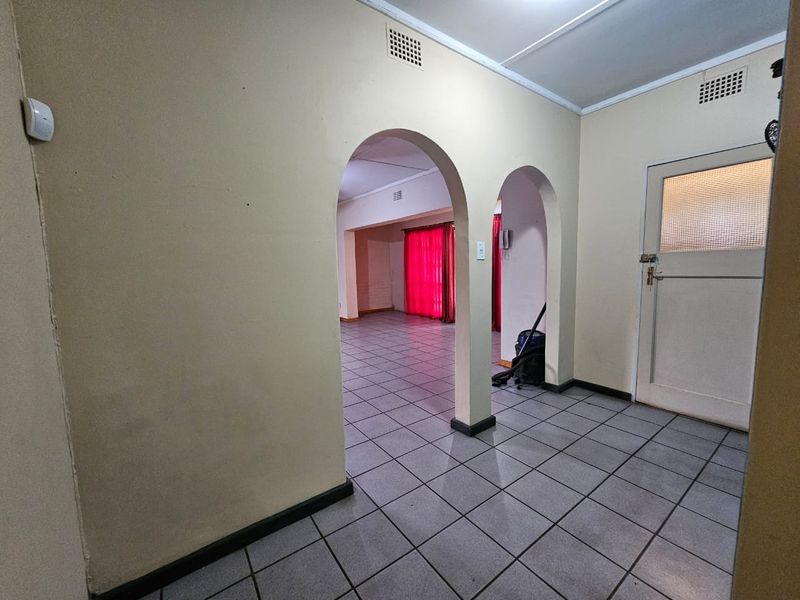 An open-plan living area featuring tiled flooring, distinctive arched doorways, and neutral wall finishes, offering a blank canvas for interior design.