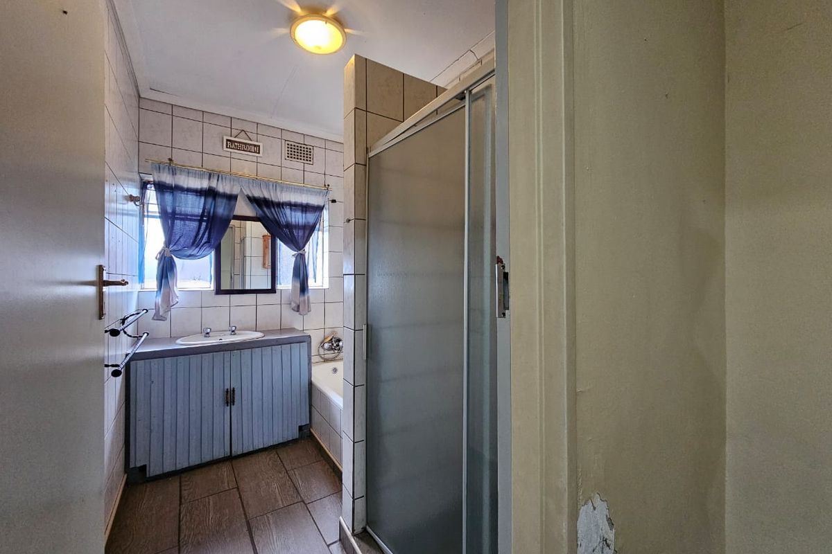A dated bathroom featuring a vanity with basin, a shower enclosure, and a bathtub, with tiled finishes throughout.