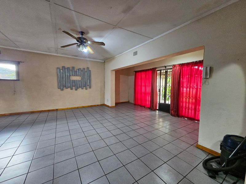 Spacious living area featuring tiled flooring, a ceiling fan, and direct access to the exterior through a security gate.