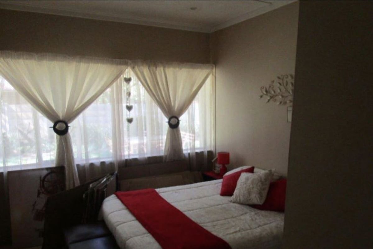 A bedroom featuring large windows with natural light, neutral wall tones, and crown molding.