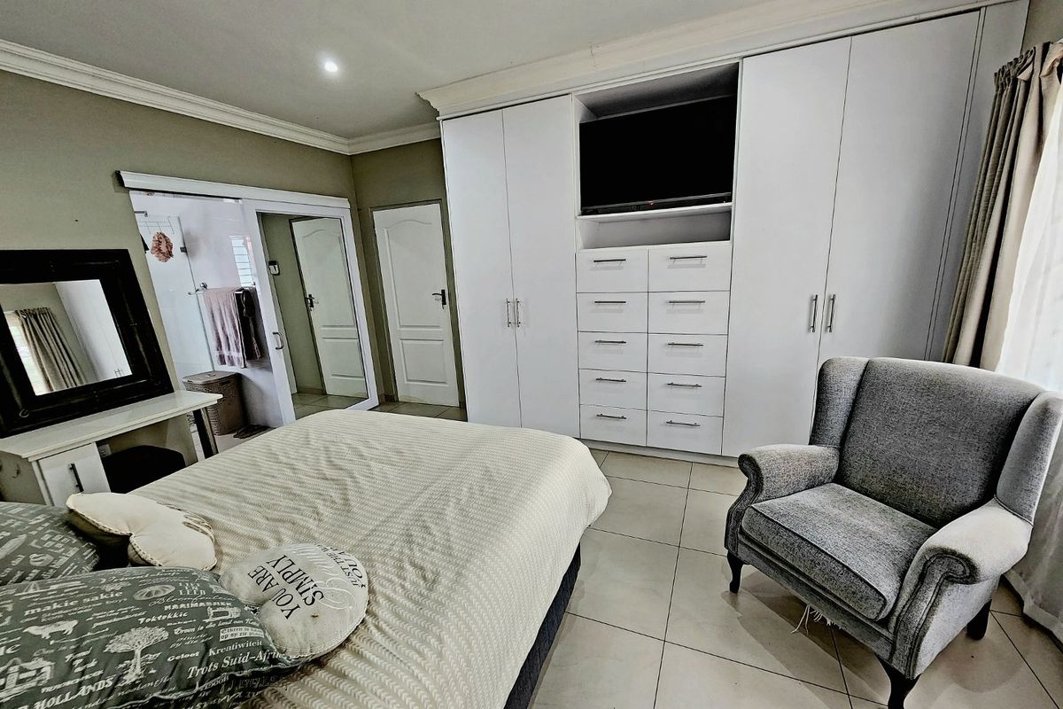 A well-maintained bedroom featuring extensive built-in white cabinetry with integrated storage and shelving, tiled flooring, and an en-suite bathroom access.