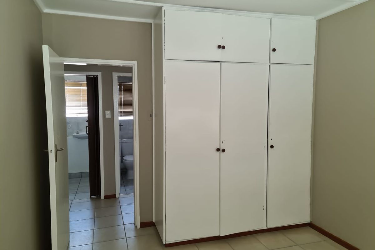 A bedroom featuring built-in floor-to-ceiling cabinetry and direct access to an adjoining bathroom with tiled flooring.
