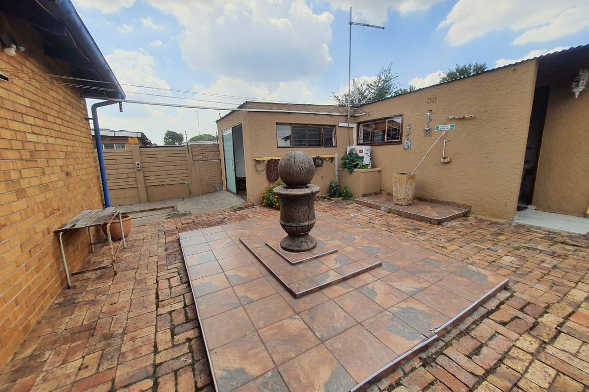 A paved rear courtyard featuring a central stone fountain, brick boundary walls, and direct access to the main dwelling structure.