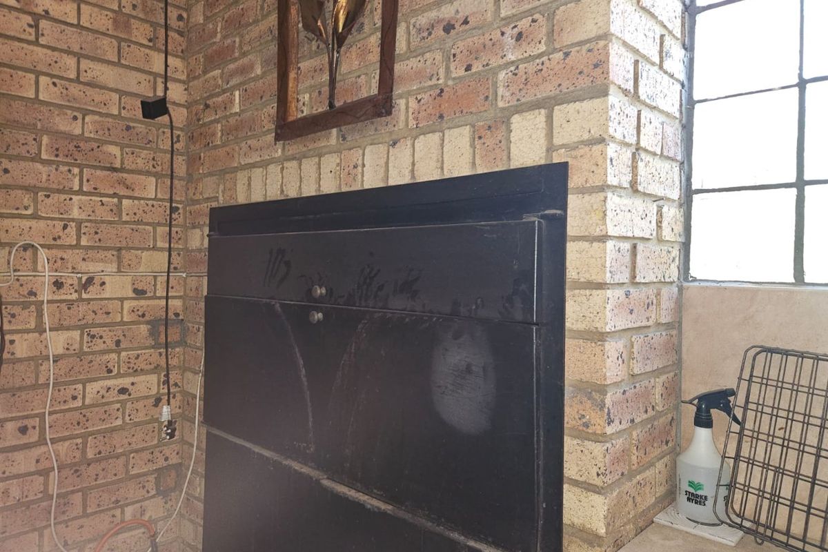 A built-in brick fireplace feature with a black metal door, situated next to a window in a living area.