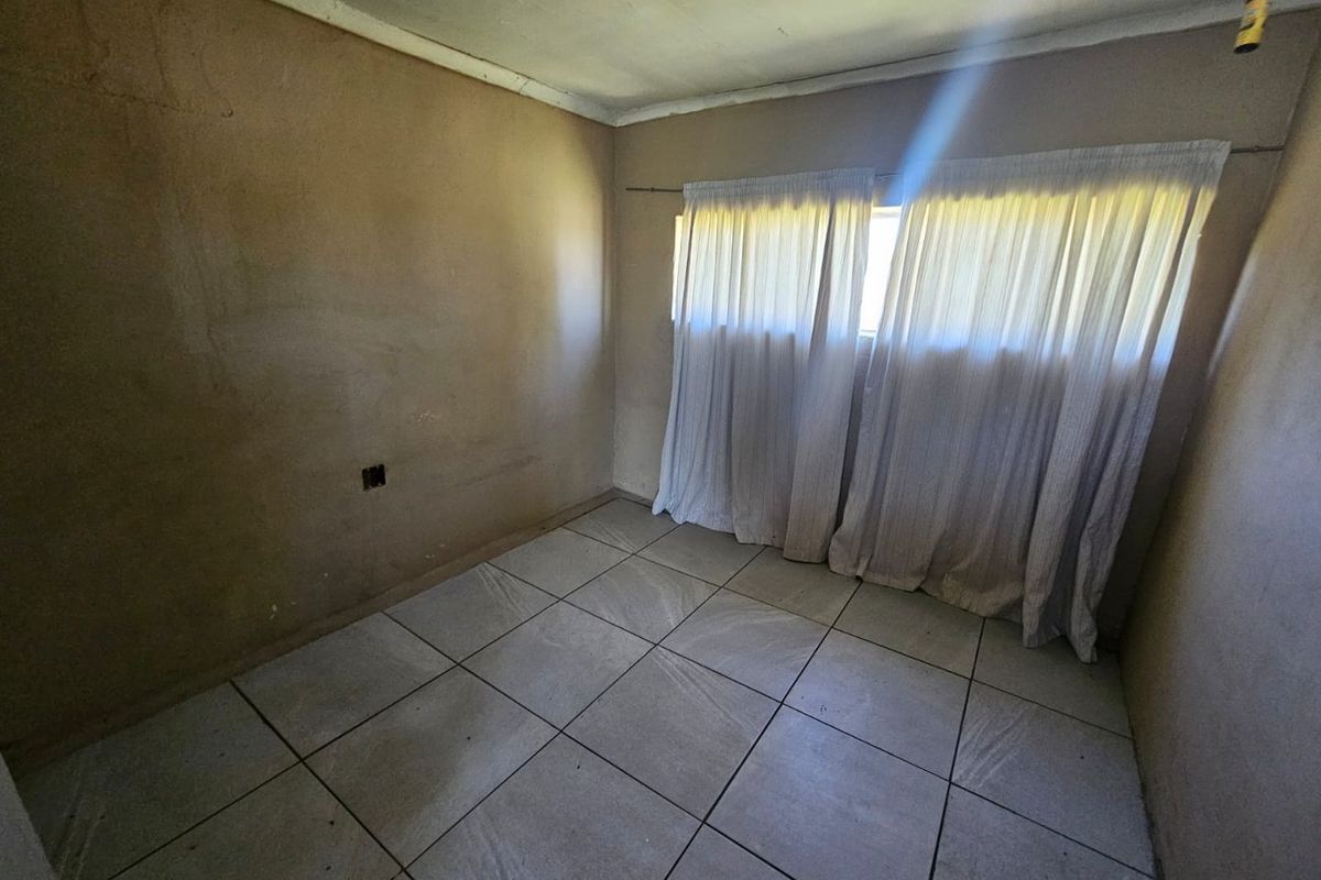 A vacant bedroom featuring tiled flooring and plain wall finishes, offering a blank canvas for renovation and interior updates.