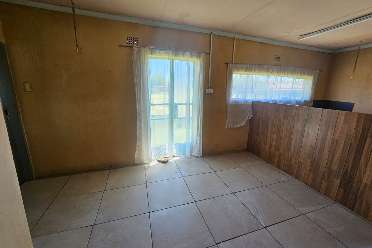 An interior living space featuring large floor tiles, wood-look wall paneling, and a glass sliding door leading to the exterior.