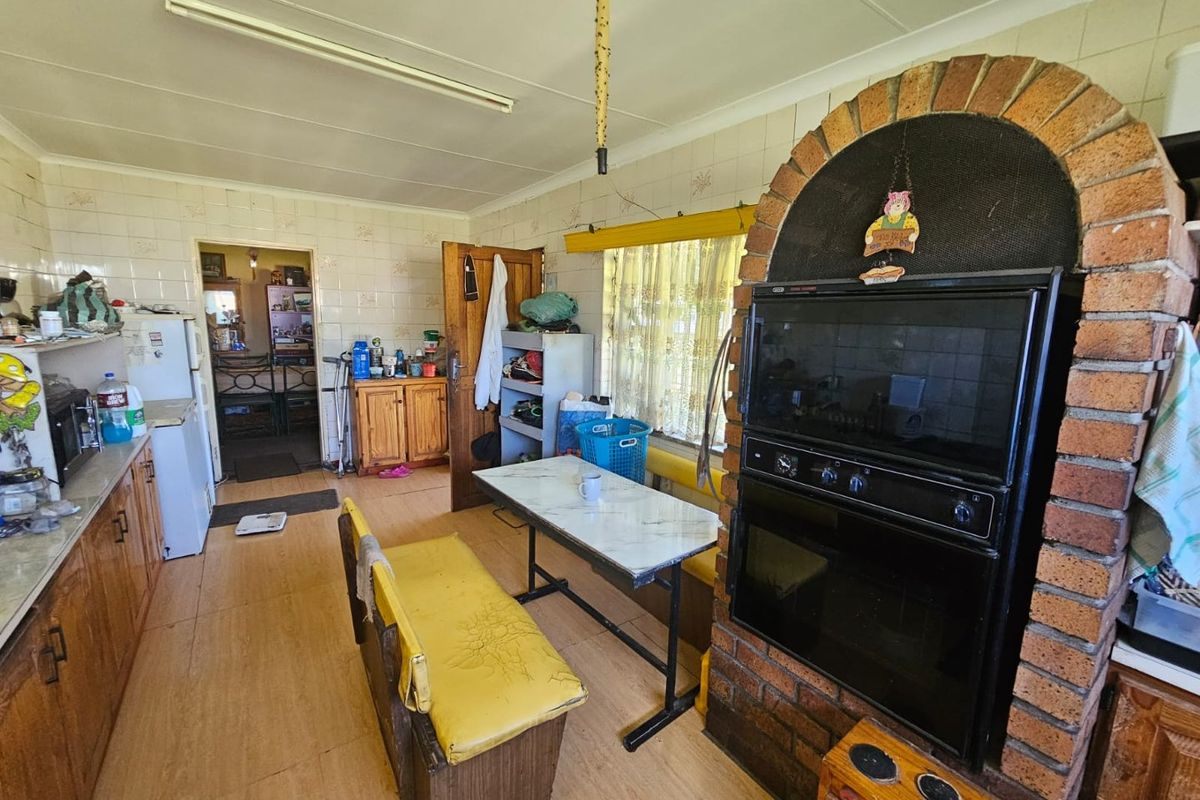 A dated kitchen featuring a built-in brick oven surround, tiled walls, and wooden cabinetry, offering a functional layout with potential for modernization.