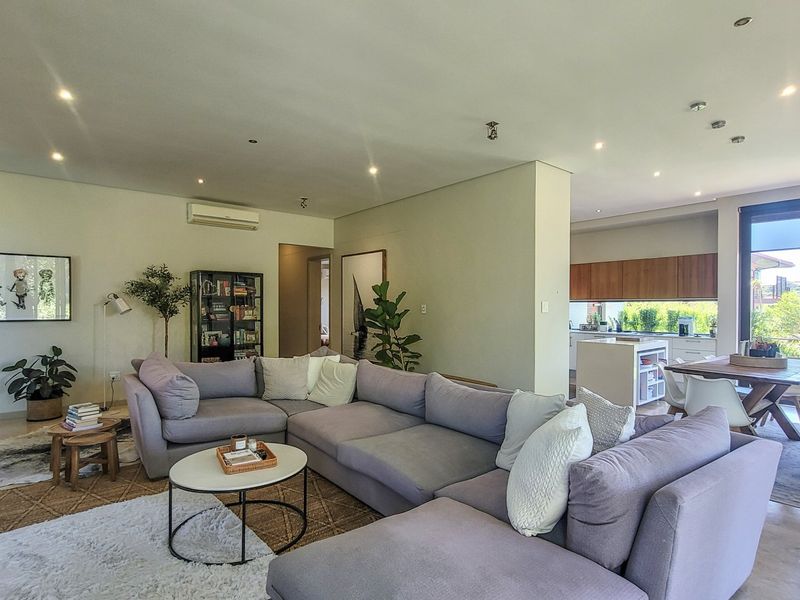 Spacious open-plan living area featuring tiled floors, recessed lighting, and a modern kitchen with built-in cabinetry, flowing seamlessly to an outdoor patio area.