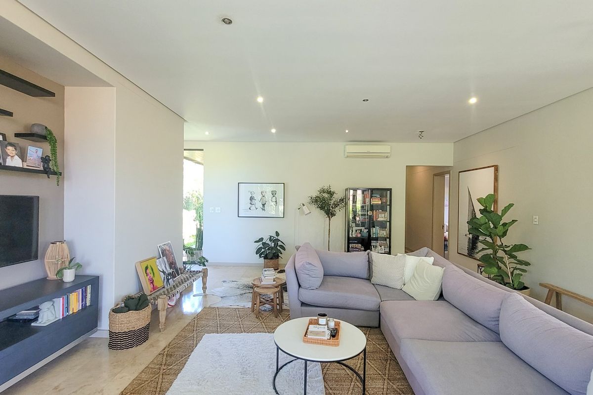 A bright and spacious living room featuring tiled flooring, recessed downlighting, and a wall-mounted air conditioning unit.