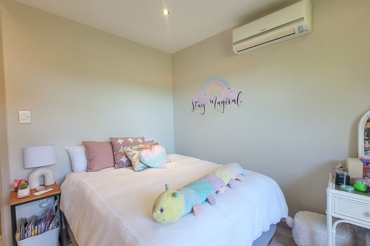 A well-maintained bedroom featuring a wall-mounted split-system air conditioner and recessed ceiling lighting.