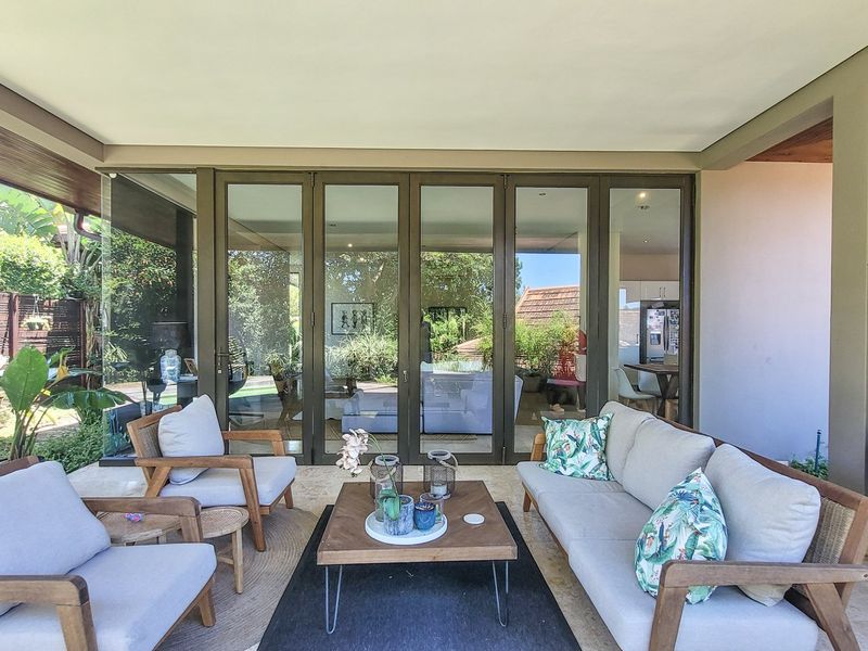 A spacious covered patio featuring large bi-fold glass doors that provide seamless indoor-outdoor flow, perfect for entertaining and relaxing in a garden setting.