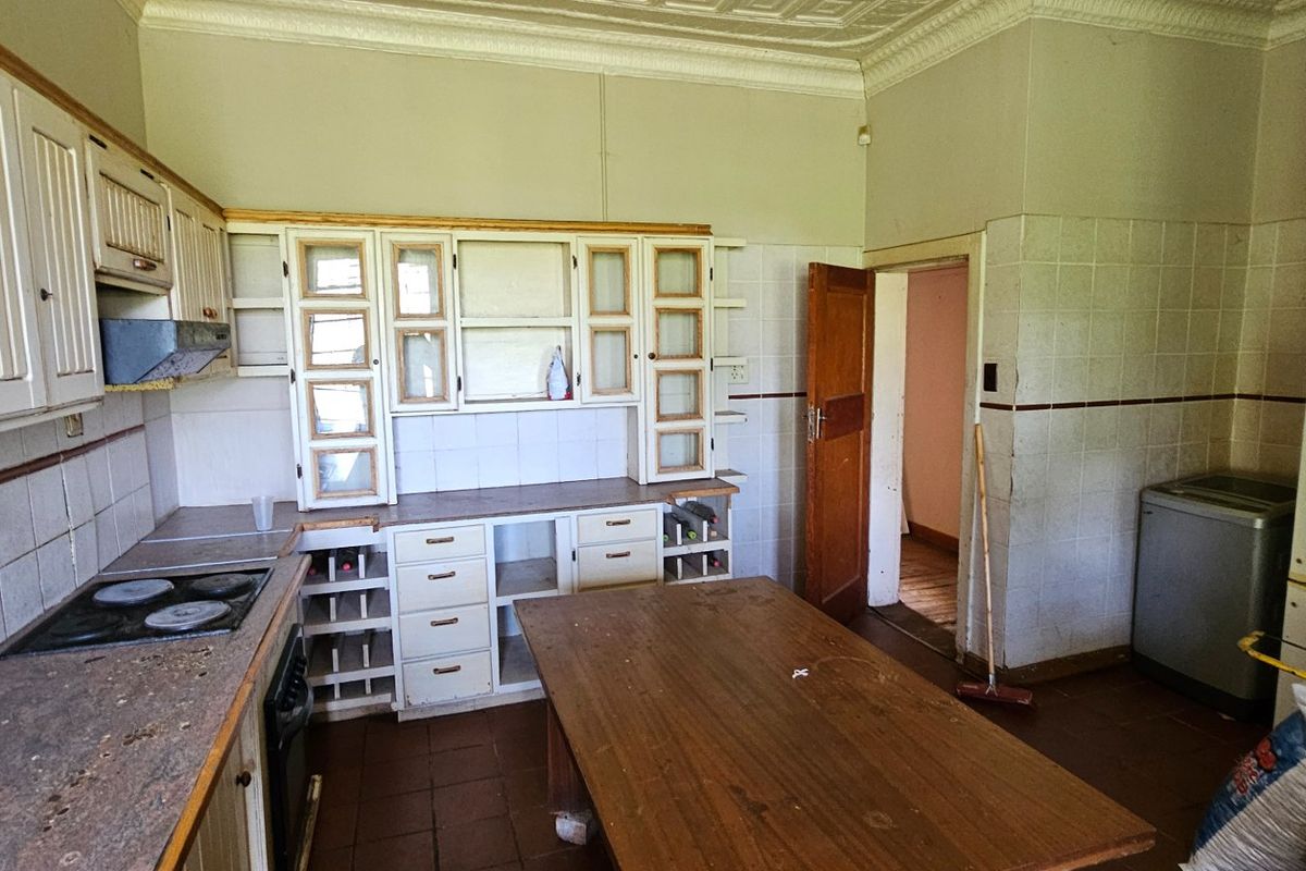 A dated kitchen featuring traditional cabinetry, tiled splashbacks, and a built-in hob, offering significant potential for renovation and modernization.