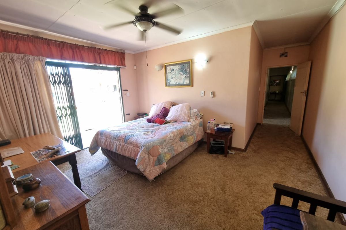 Spacious bedroom featuring carpeted flooring, a ceiling fan, and a sliding door providing access to the exterior.
