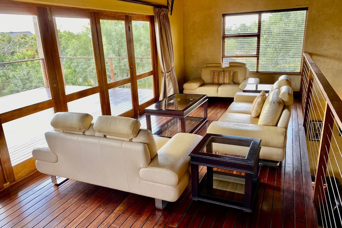 Spacious living area featuring rich timber flooring, large wooden-framed glass sliding doors opening to a balcony, and abundant natural light.