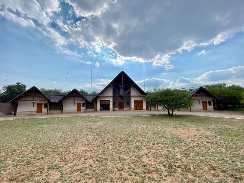 Spacious exterior front view of a large residential property featuring a distinctive A-frame architectural design, multiple entry points, and a wide gravel driveway.