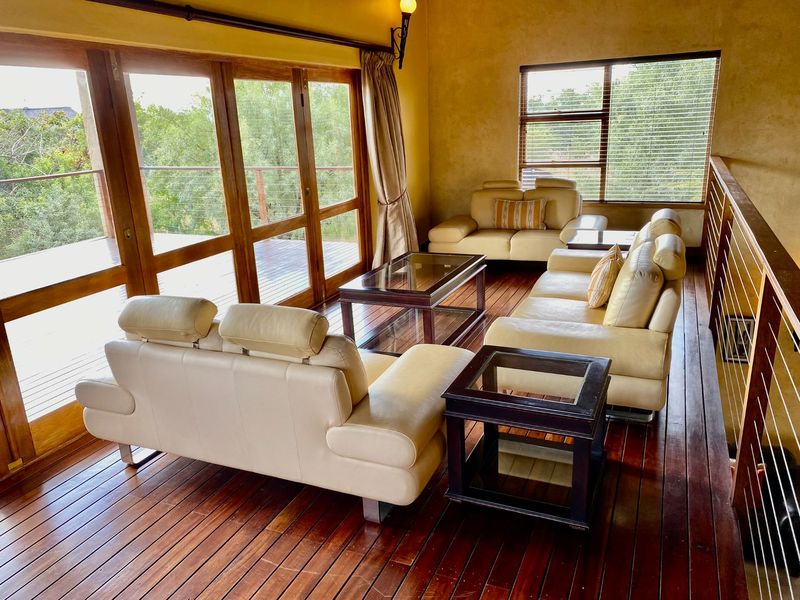 Spacious living area featuring rich timber flooring, large wooden-framed glass sliding doors opening to a balcony, and abundant natural light.